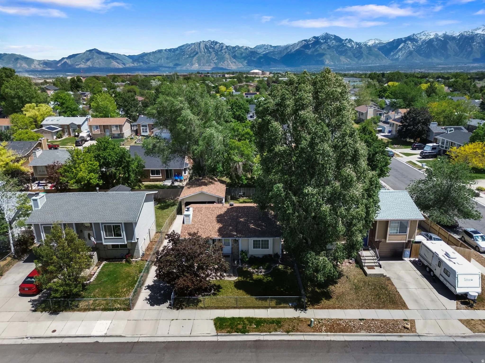 Residential street featuring two properties with established landscaping and mountain scenery