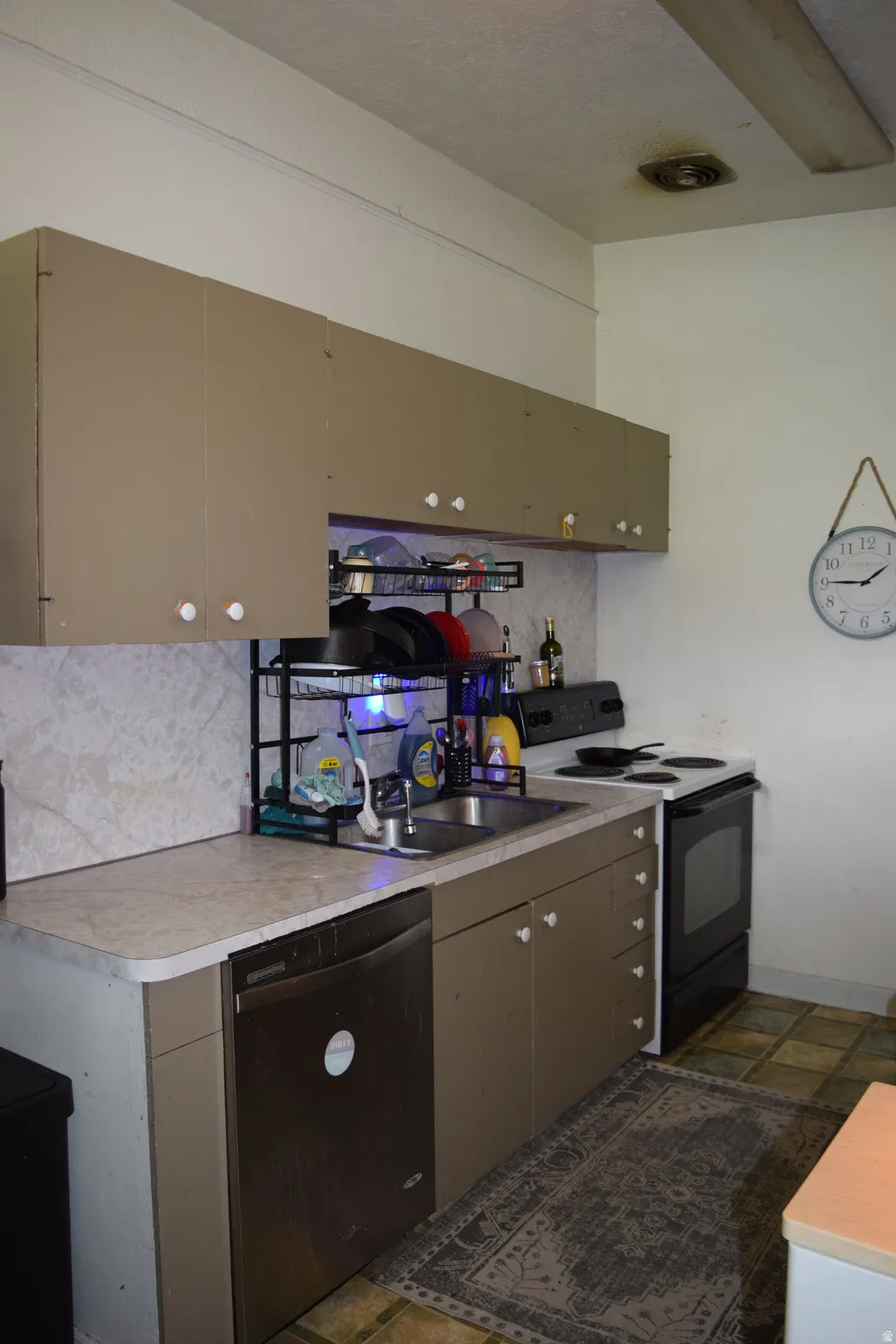 Functional kitchen featuring a stainless steel dishwasher, double basin sink, and a four-burner electric range with oven