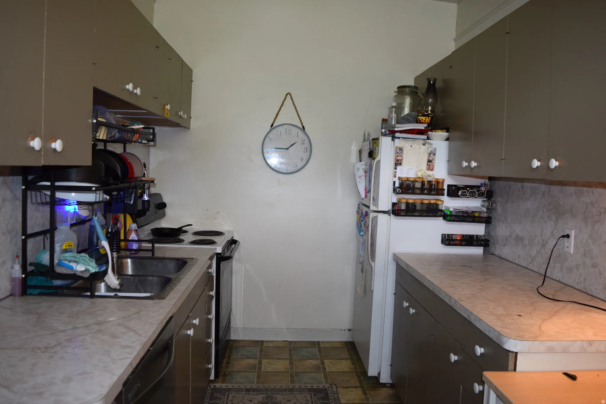 Galley kitchen with dual-basin sink, laminate countertops, and ample upper and lower cabinetry