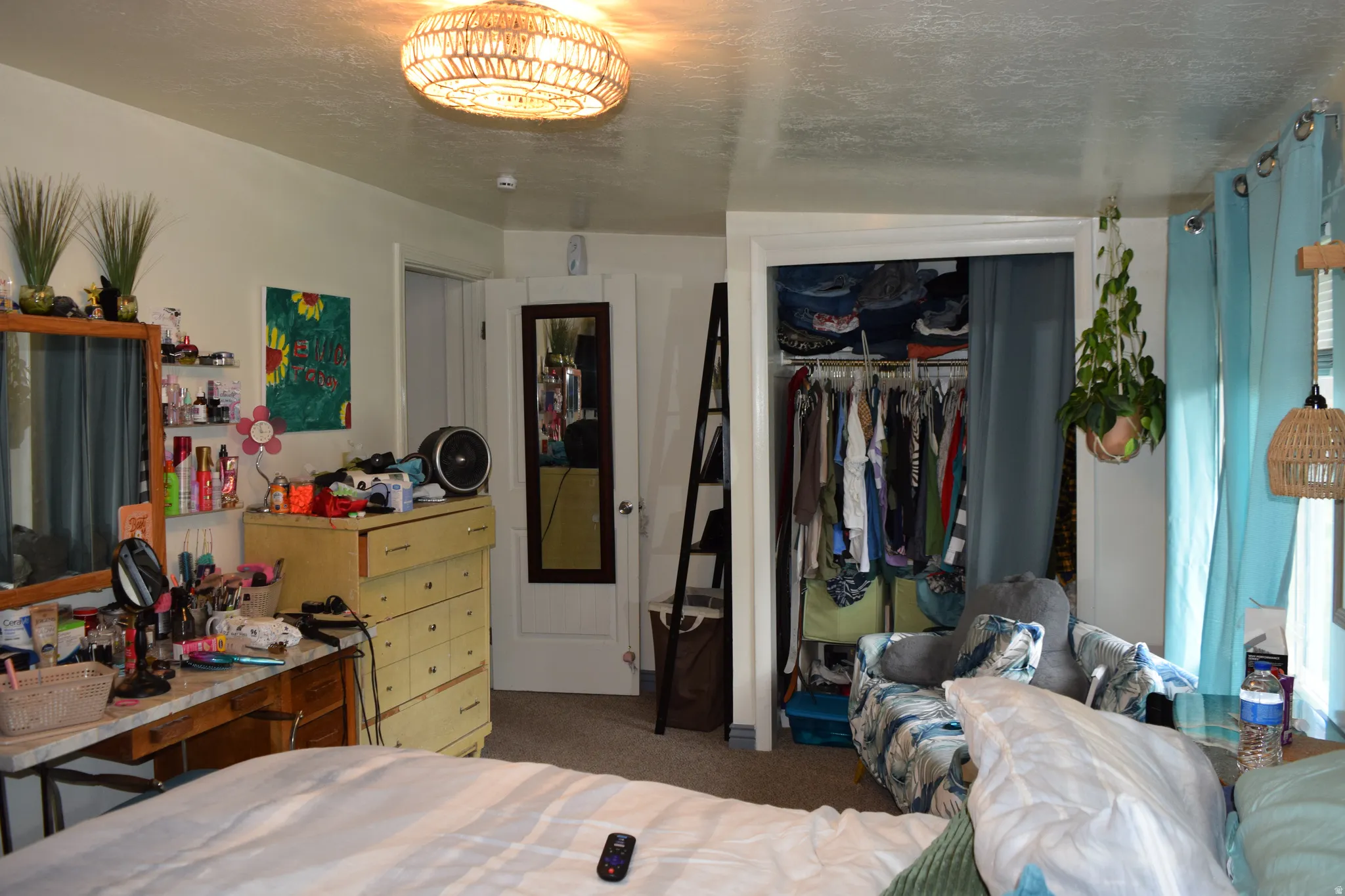 Carpeted room with a flush-mount woven ceiling light fixture, a closet with bifold doors, and an additional doorway