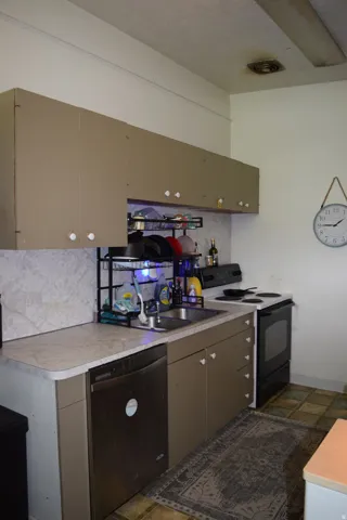 Functional kitchen featuring a stainless steel dishwasher, double basin sink, and a four-burner electric range with oven