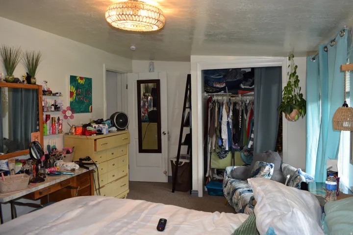Carpeted room with a flush-mount woven ceiling light fixture, a closet with bifold doors, and an additional doorway