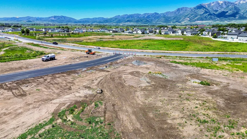 Expansive undeveloped land featuring a newly paved roadway and distant mountain range backdrop
