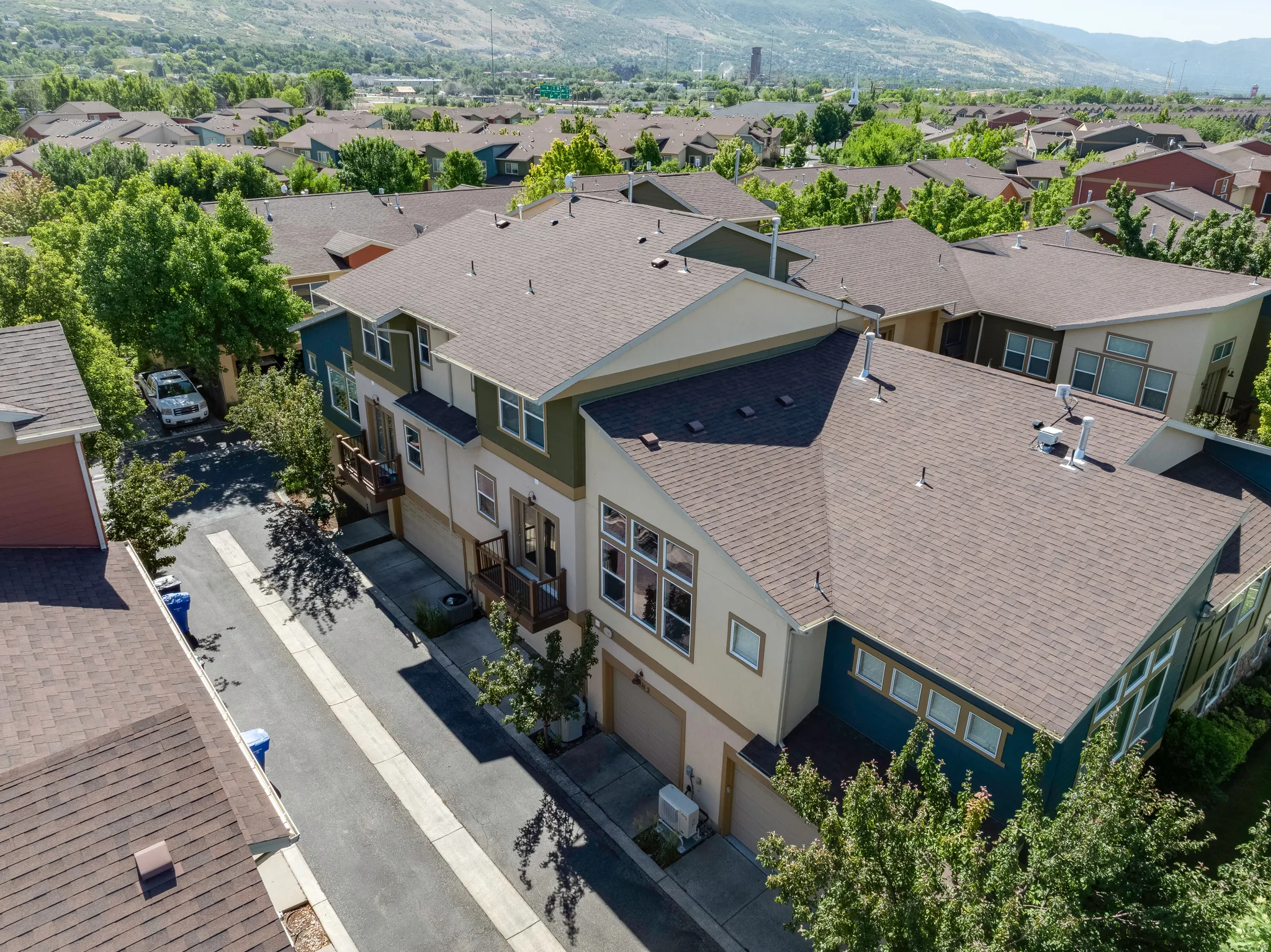 Multi-level townhome featuring a neutral-toned exterior with dark green and blue accents