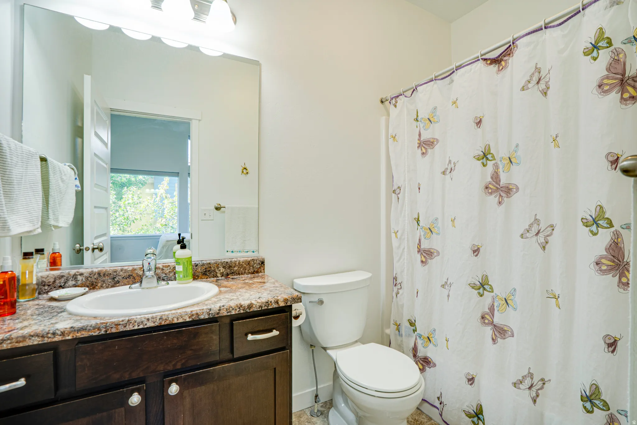 Bathroom featuring a dark wood-finish vanity with ample storage, a speckled countertop, and a white oval sink with a chrome faucet
