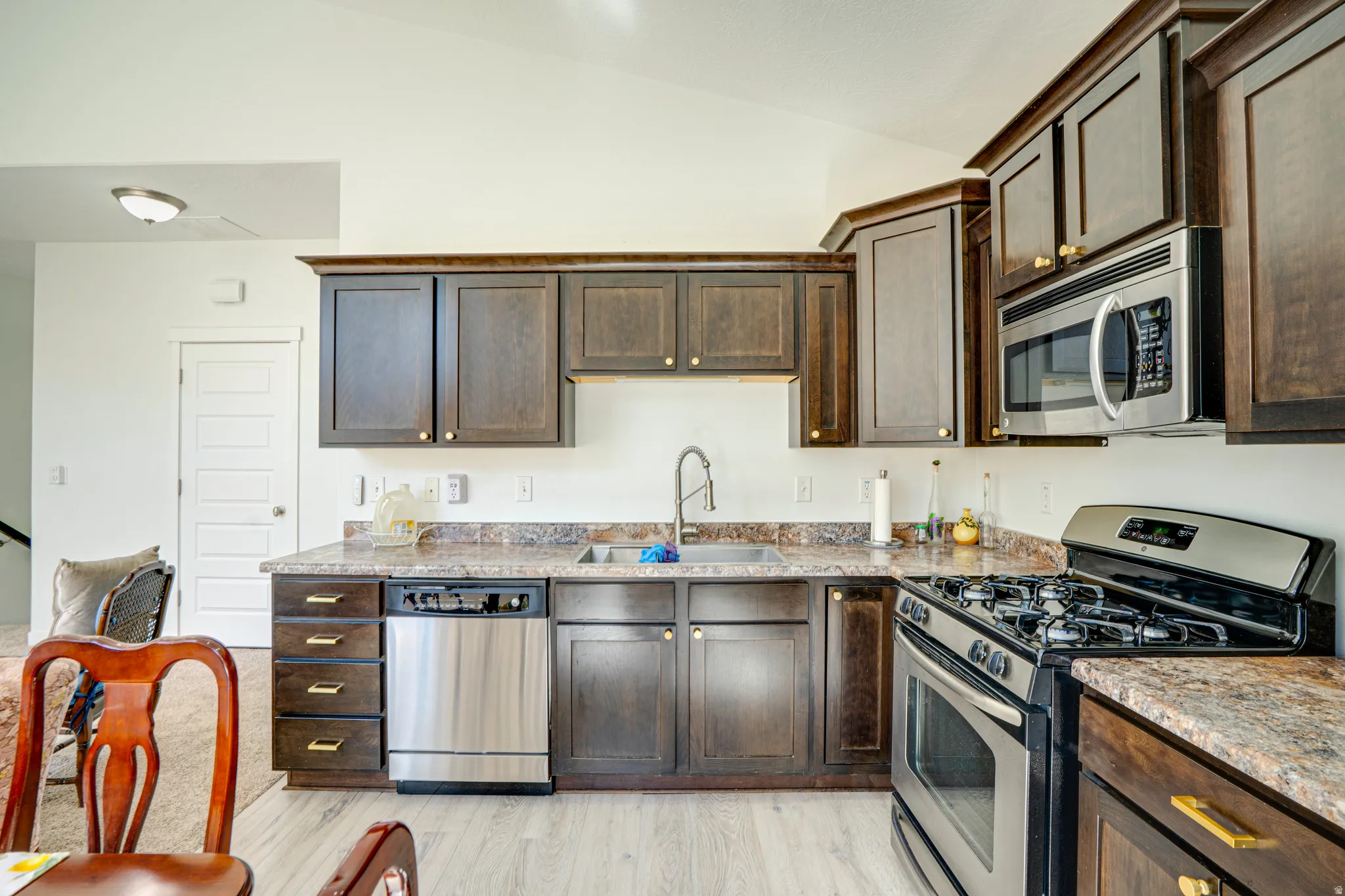 Kitchen featuring dark wood cabinetry, stainless steel appliances, and a light wood-finish flooring