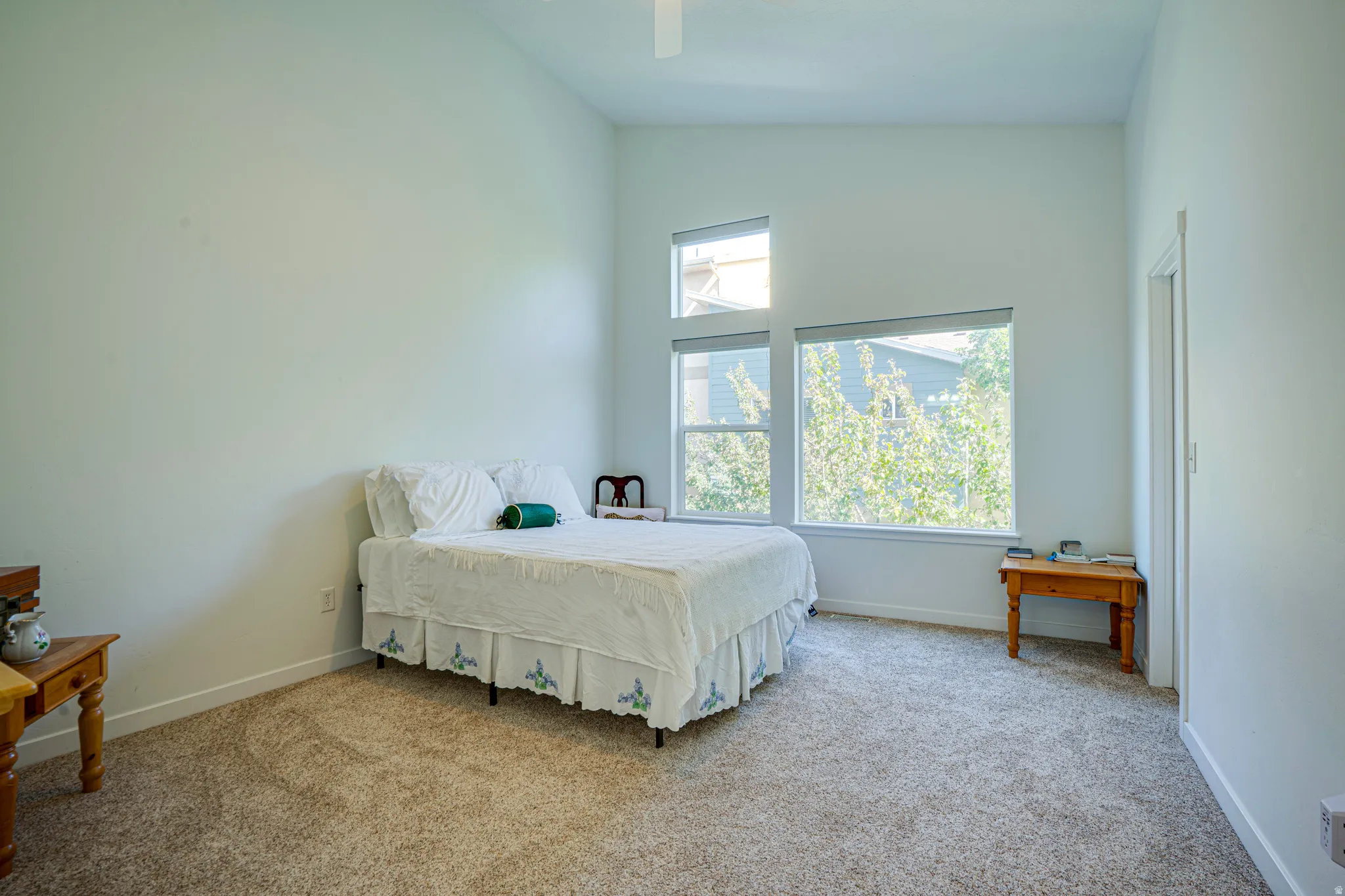 Interior room featuring high ceilings, multiple windows, light-colored walls, and carpeting