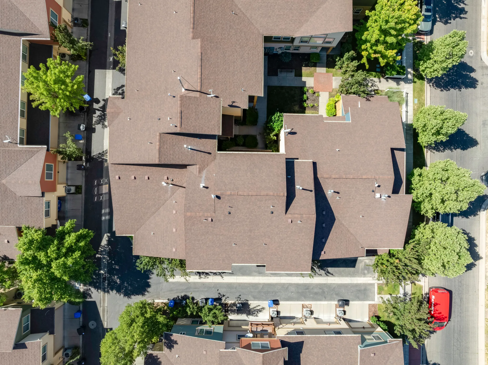 Aerial perspective showcasing a complex of buildings with various rooflines and brown asphalt shingle roofs