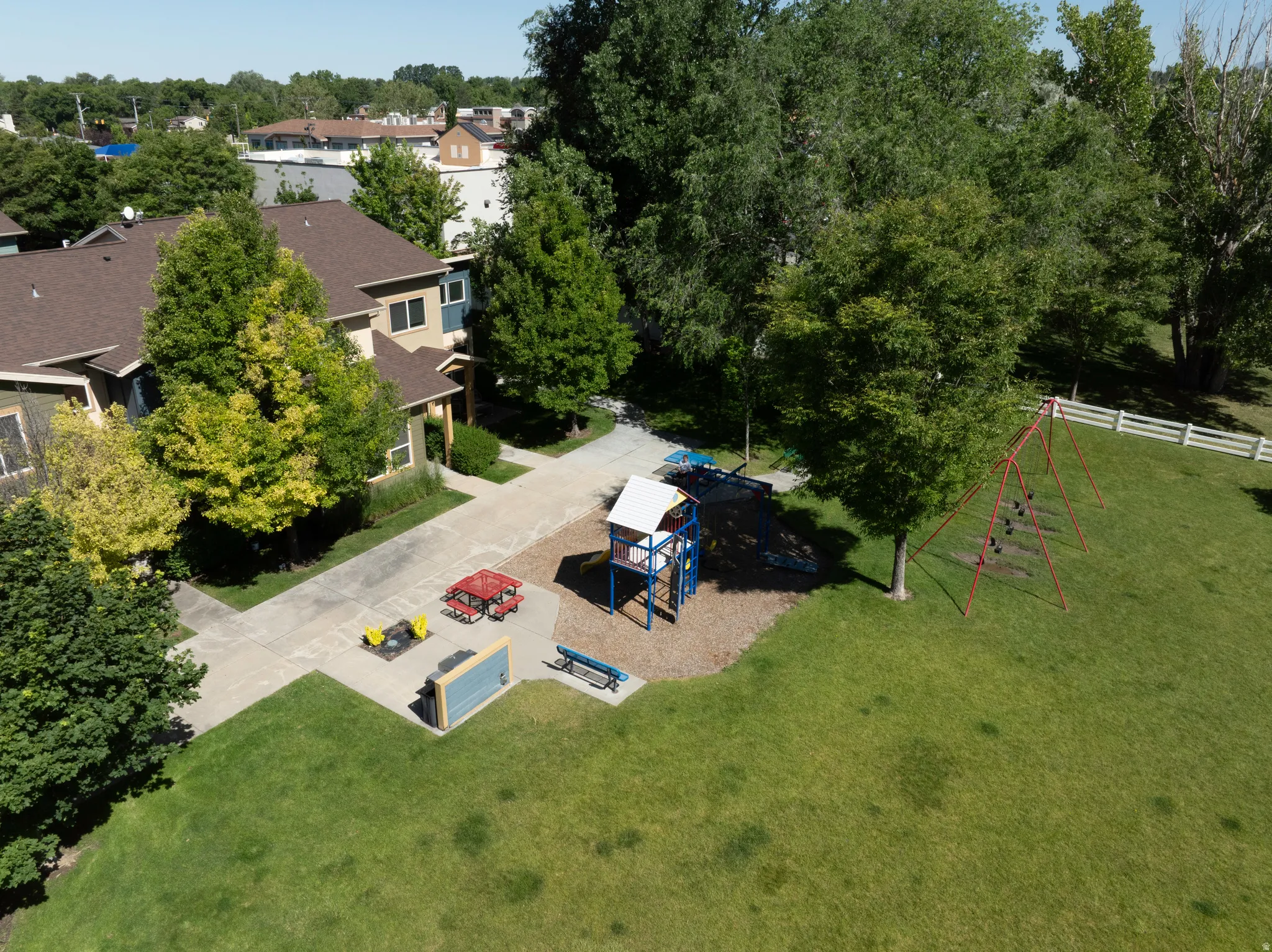 Expansive green space featuring a playground with a slide structure and a separate swing set