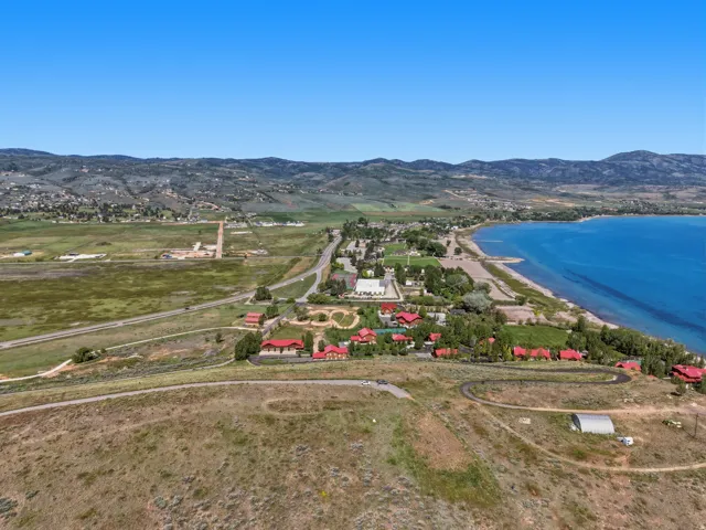 Expansive waterfront property featuring clear blue water, a sandy shoreline, and distant mountain ranges