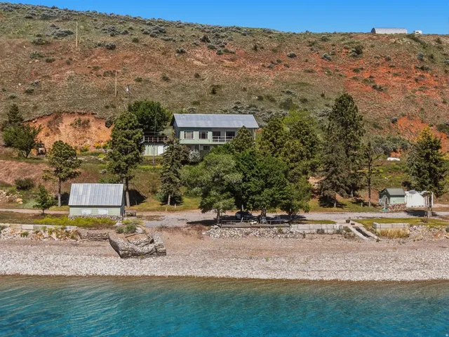 Lakeside property featuring a multi-level residence with light green siding and a grey roof