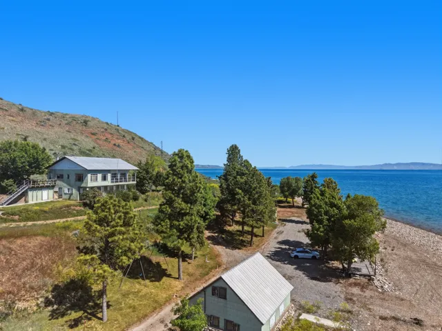 Lakeside property featuring a multi-story residence with a balcony and an additional structure