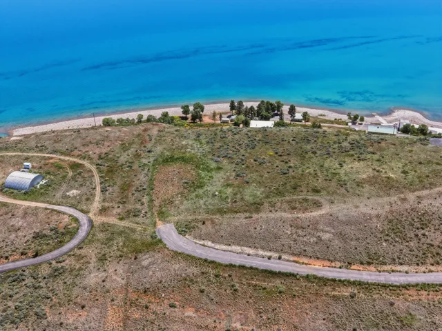 Expansive waterfront land featuring a private beach, multiple structures, and a paved access road