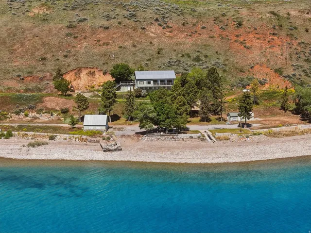 Waterfront property featuring a two-story residence, a detached auxiliary building, and a private shoreline