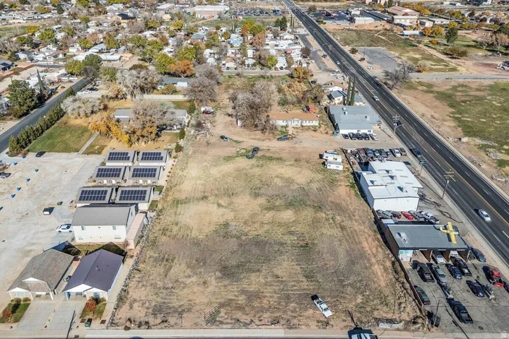 Expansive undeveloped land parcel featuring direct road frontage, perimeter fencing, and established surrounding commercial properties