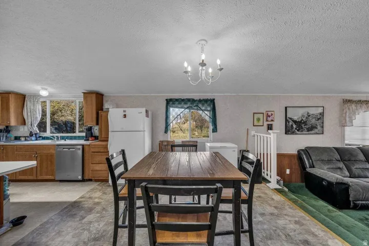 Open concept kitchen and dining area with wood-finish cabinetry, stainless steel dishwasher, and white appliances