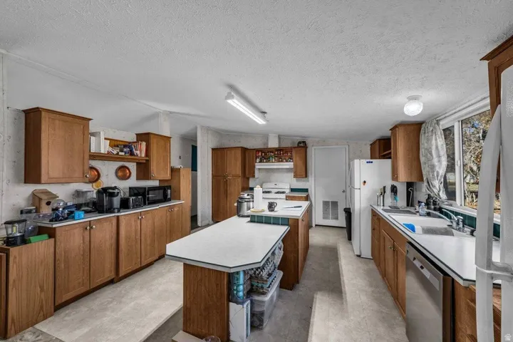 Spacious kitchen featuring extensive wood cabinetry, white countertops, a central island, and multiple windows