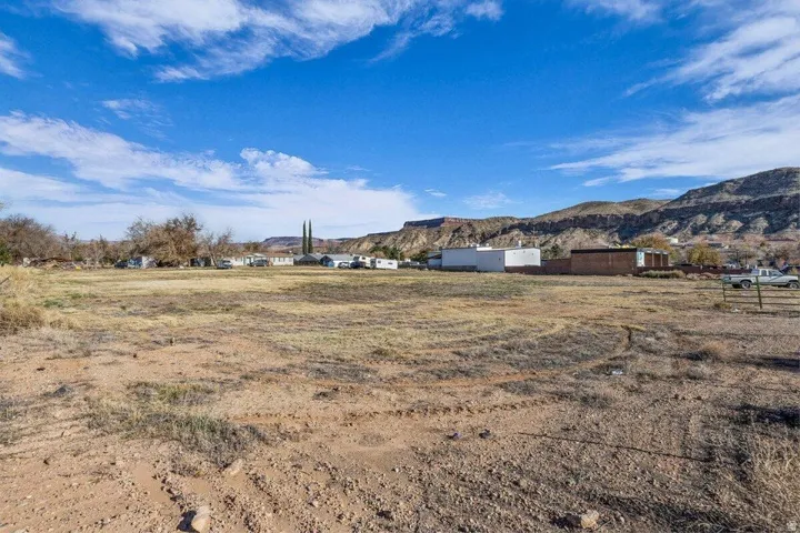 Expansive undeveloped lot featuring a natural terrain, distant mountain backdrop, and clear sky