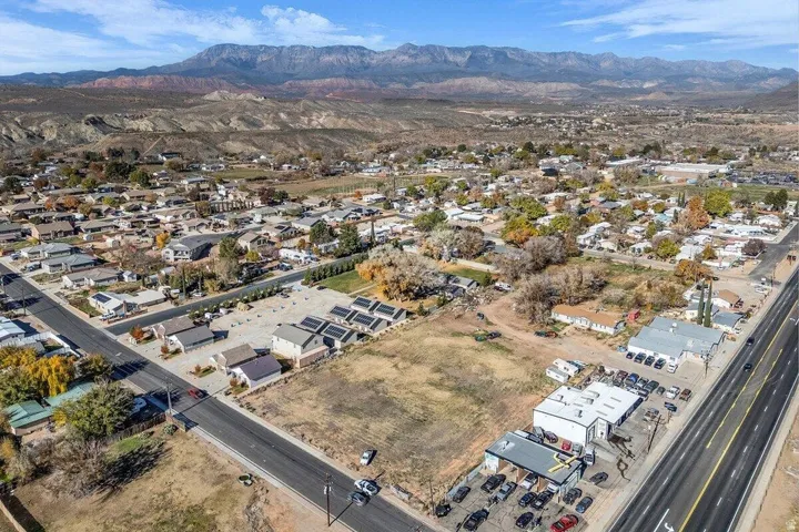 Expansive land parcel featuring established residential infrastructure, direct road frontage, and distant mountain backdrop
