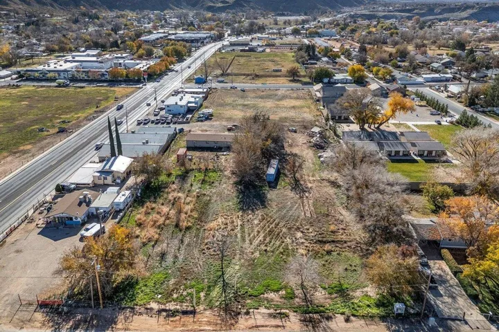 Expansive undeveloped land featuring a cleared section, scattered mature trees, and visible street frontage