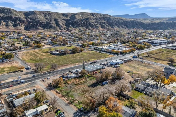 Expansive land parcels with mountainous backdrop, featuring highway frontage, commercial buildings, and nearby residential areas