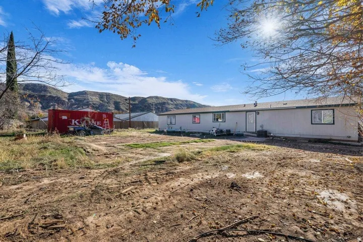 Expansive lot with a single-story dwelling featuring a light-colored exterior and multiple windows