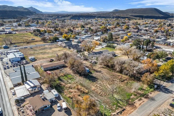 Expansive undeveloped land parcel featuring mature trees, a clear level area, and mountain backdrop