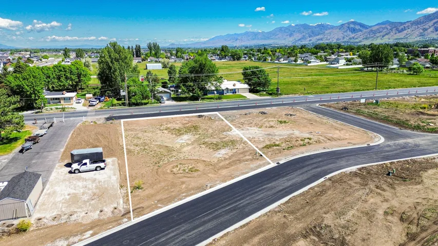 Expansive undeveloped land parcel featuring clearly marked boundaries, new asphalt road frontage, and a backdrop of distant mountains