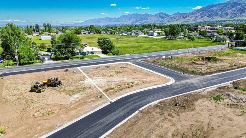 Grades land parcel with established road frontage, bordered by a newly paved street