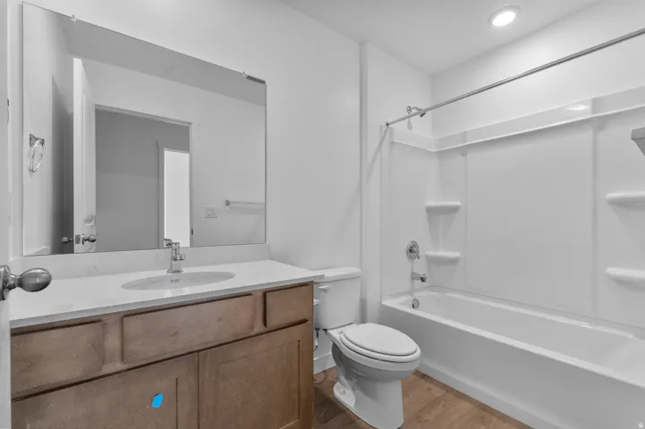 Bathroom featuring a wood-finish vanity with a light-toned countertop, an undermount sink, and a large wall-mounted mirror