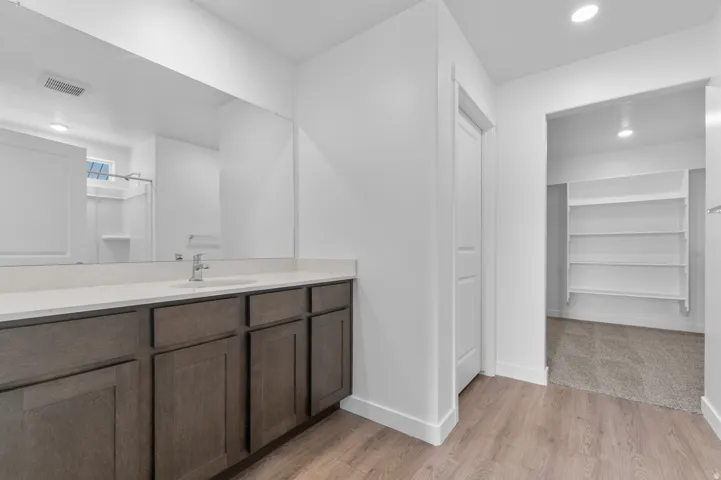 Bathroom vanity featuring a light-toned countertop, wood-finish cabinetry, and an integrated sink with a chrome faucet