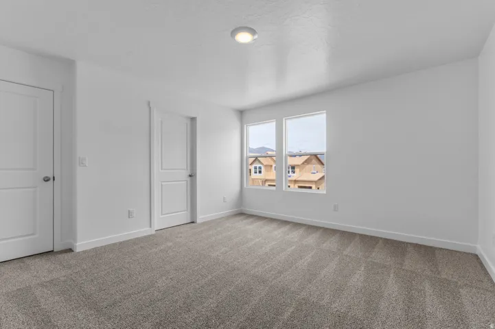 Room featuring light grey carpeting, white walls, and two white panel doors