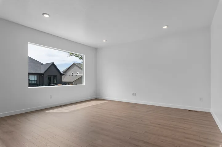 Spacious room featuring wood-finish flooring, white walls, and recessed lighting