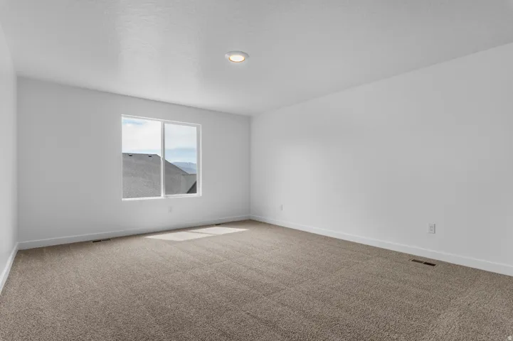 Carpeted room with a large window and white walls