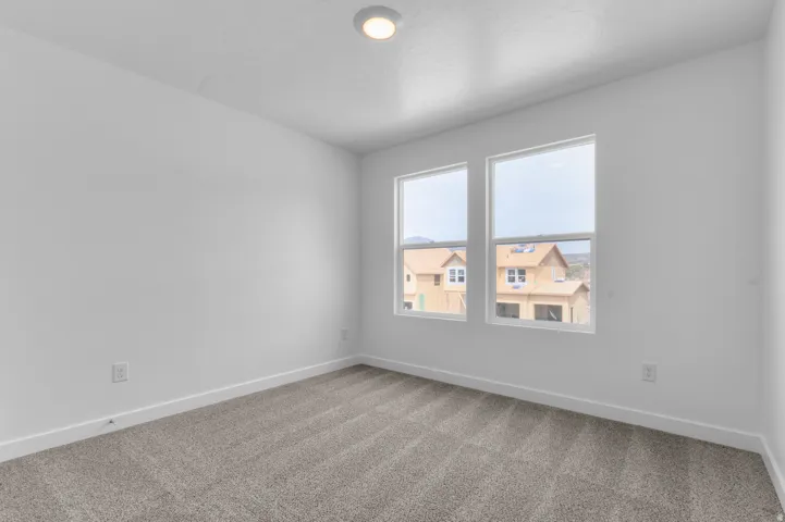 Room featuring two windows, recessed ceiling lighting, light gray carpet, and white baseboards