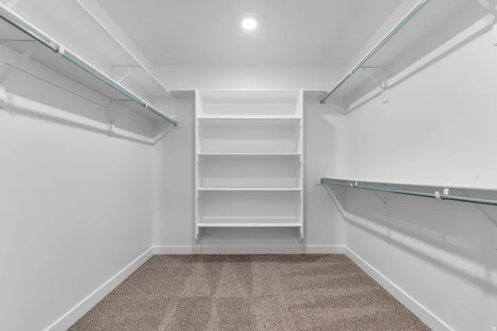Walk-in closet featuring built-in shelving, dual hanging rods, and recessed ceiling lighting