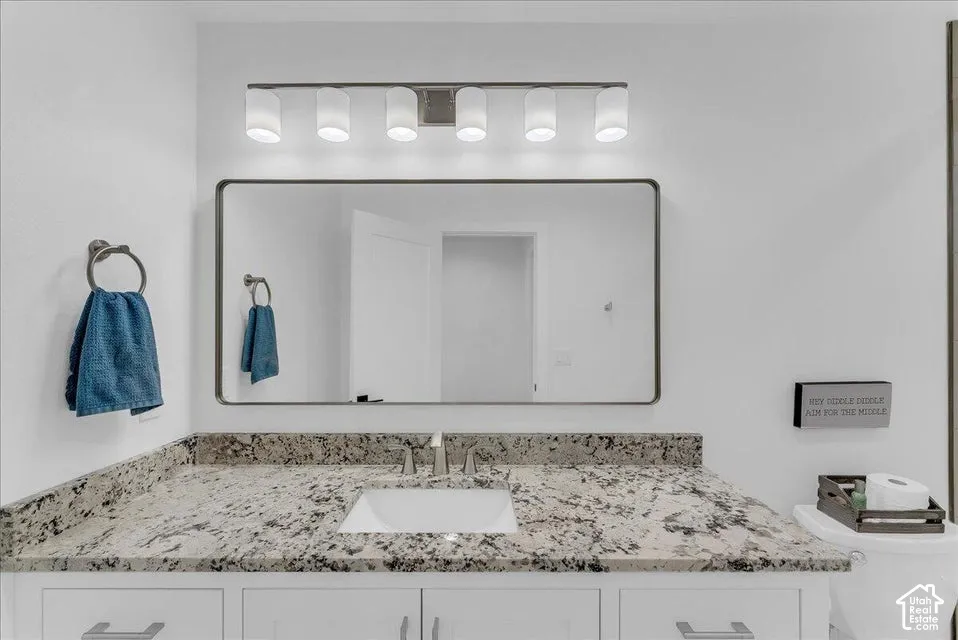 Bathroom vanity featuring a rectangular undermount sink, dual chrome faucets, and a light-toned speckled countertop
