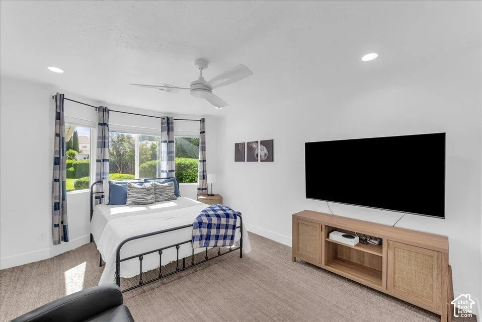 Bay window with multiple glass panes, recessed lighting, ceiling fan, carpet flooring, and a media console with integrated storage