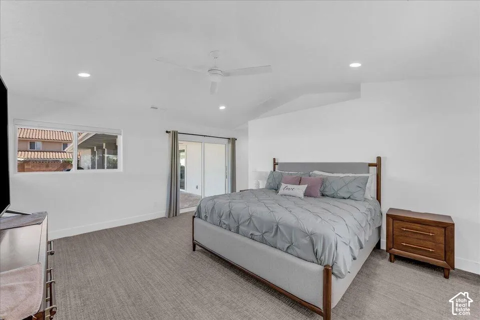 Spacious room featuring light-toned carpet flooring, bright white walls, and a white ceiling fan