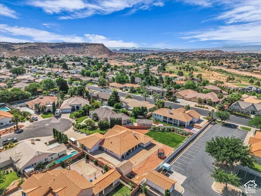 Expansive residential area with mature landscaping, multiple properties with tile roofs, and surrounding mountainous terrain