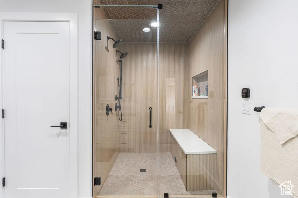 Glass-enclosed shower with multiple showerheads, a built-in bench, and a tiled niche
