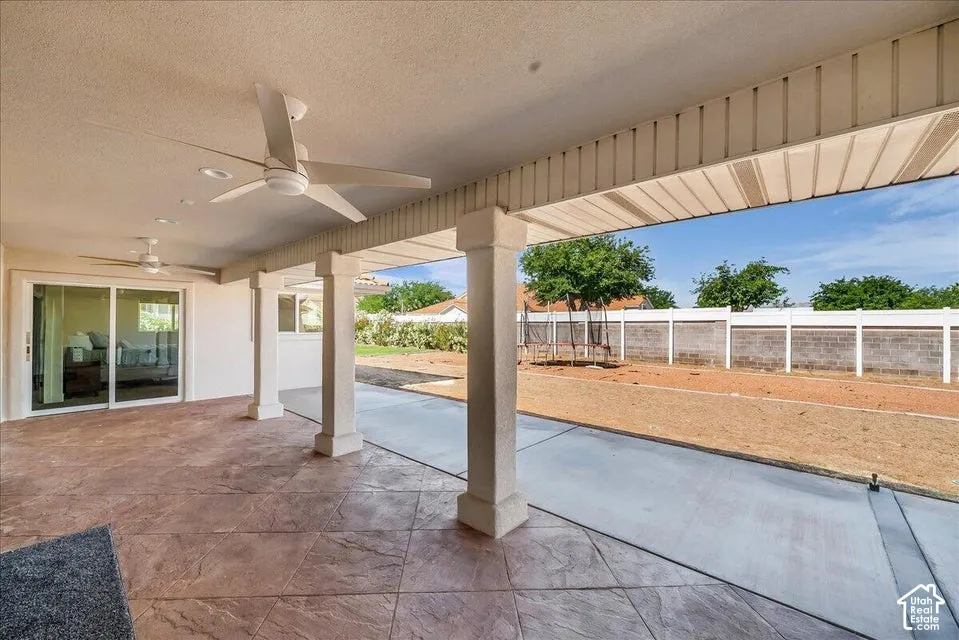 Expansive covered patio featuring stamped concrete flooring, multiple ceiling fans, recessed lighting, and a sliding glass door entry