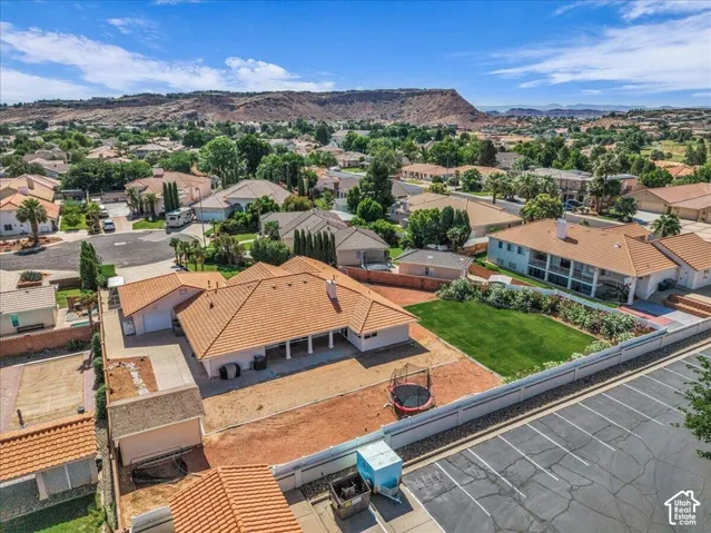 Expansive residential property featuring a large backyard with a manicured lawn, a detached garage, and a tiled roof main residence