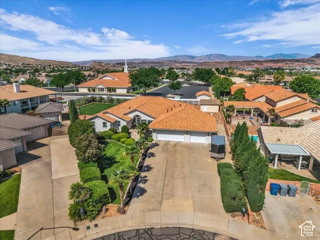 Single-story residence featuring a two-car garage, mature landscaping, and an expansive driveway