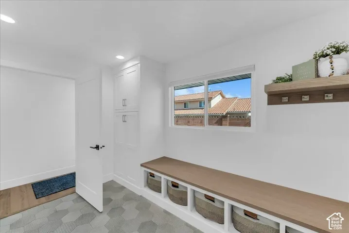Entryway featuring a built-in bench with storage, integrated shelving, and white cabinetry