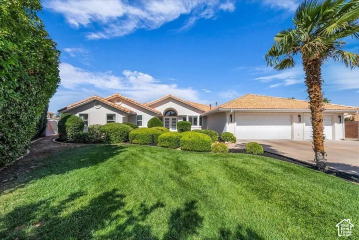 Mediterranean-style residence featuring a stucco exterior, tiled roof, and an arched entry