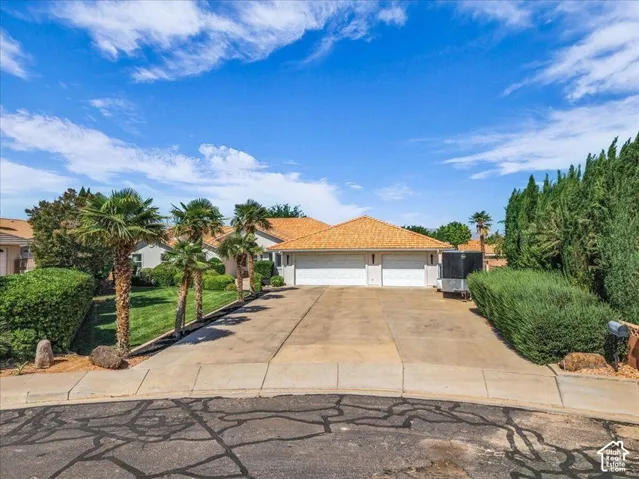 Single-story residence featuring a tile roof, a two-car garage with white doors, and a concrete driveway