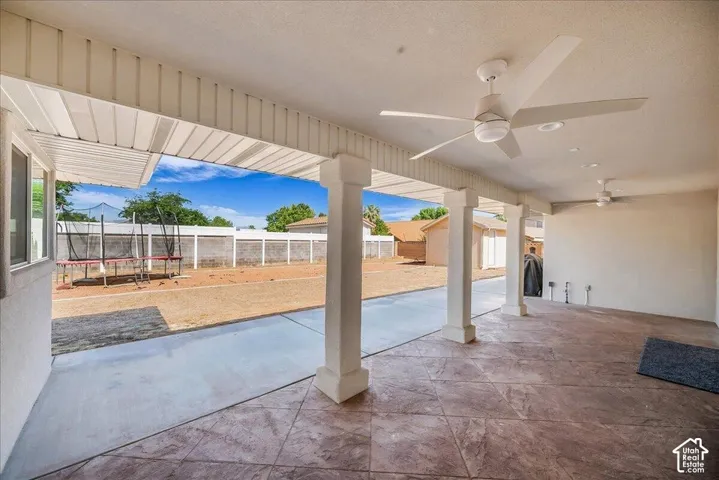 Expansive covered patio featuring stamped concrete flooring, multiple ceiling fans, recessed lighting, and support columns