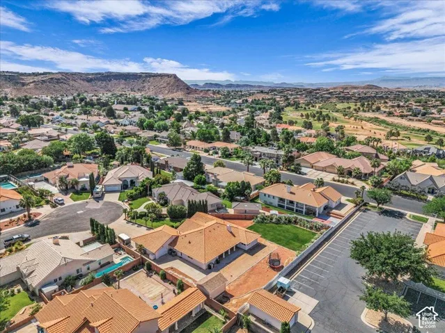 Expansive residential area with mature landscaping, multiple properties with tile roofs, and surrounding mountainous terrain