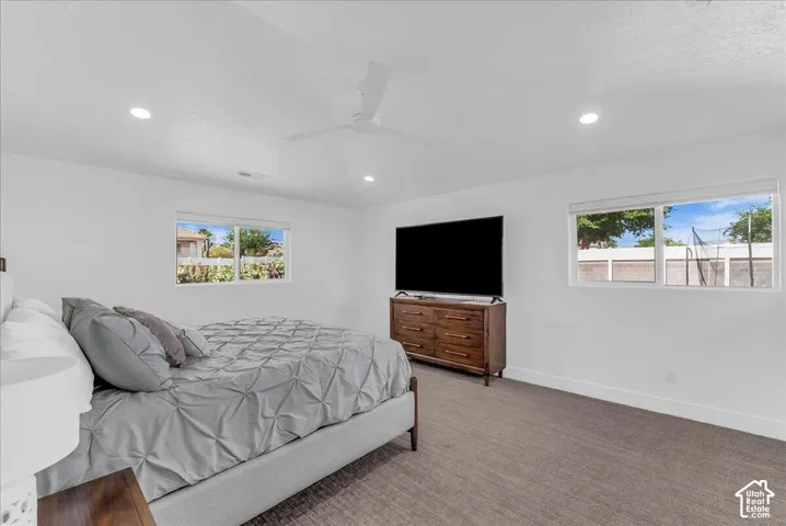 Spacious bedroom featuring recessed lighting, a ceiling fan, two large windows, white trim, and neutral-toned carpeting